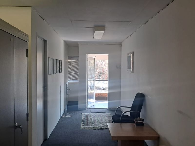 A functional office space featuring carpeted flooring, built-in storage, and direct access to an outdoor balcony area.