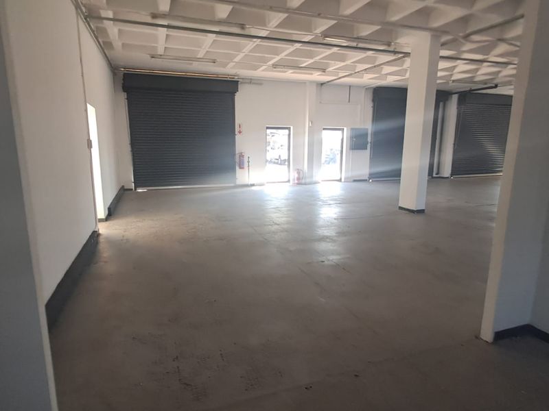 Spacious industrial warehouse unit featuring high ceilings, concrete flooring, and multiple roller shutter doors for efficient access and logistics.