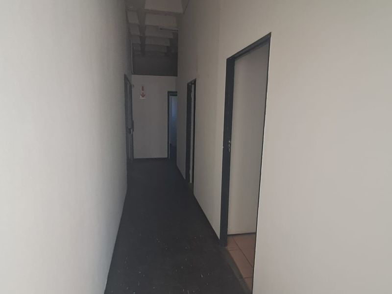 A functional industrial hallway featuring exposed concrete ceiling elements and multiple access points to adjacent rooms.