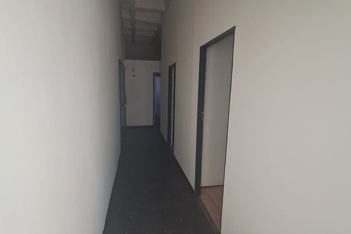 A functional industrial hallway featuring exposed concrete ceiling elements and multiple access points to adjacent rooms.