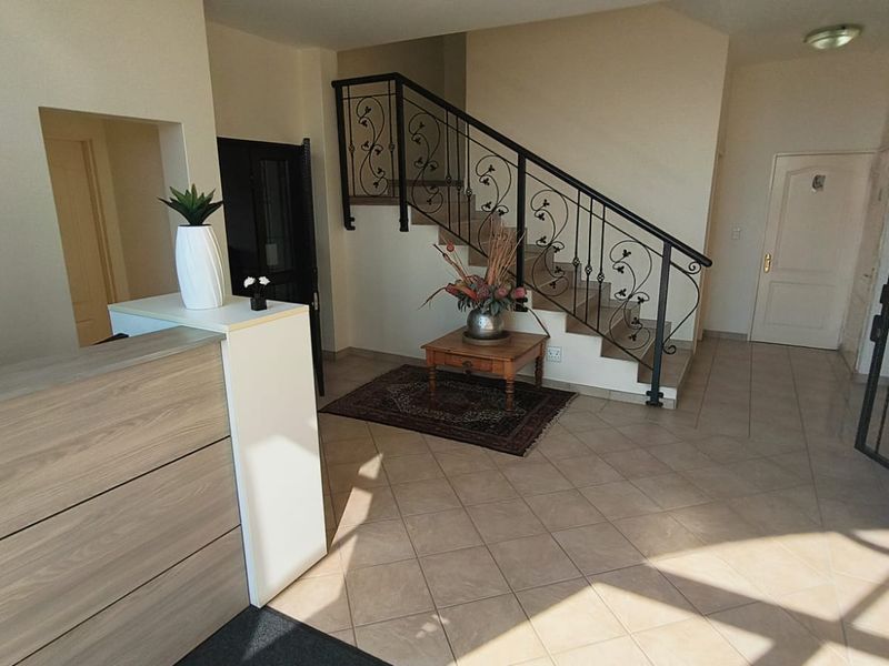 Welcoming office entrance area featuring tiled flooring, a reception desk, and a decorative wrought iron staircase railing.