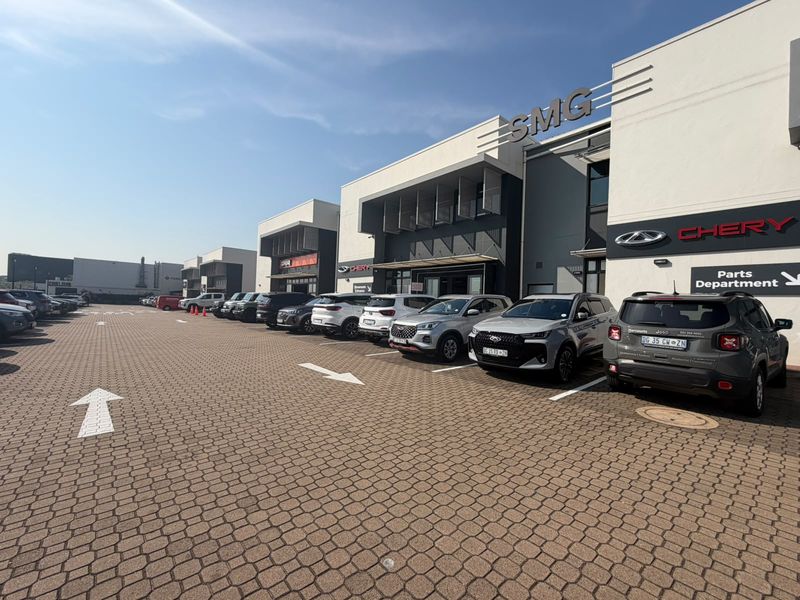 A well-maintained commercial retail property featuring a paved parking lot and modern building facade with clear signage for the dealership and parts department.