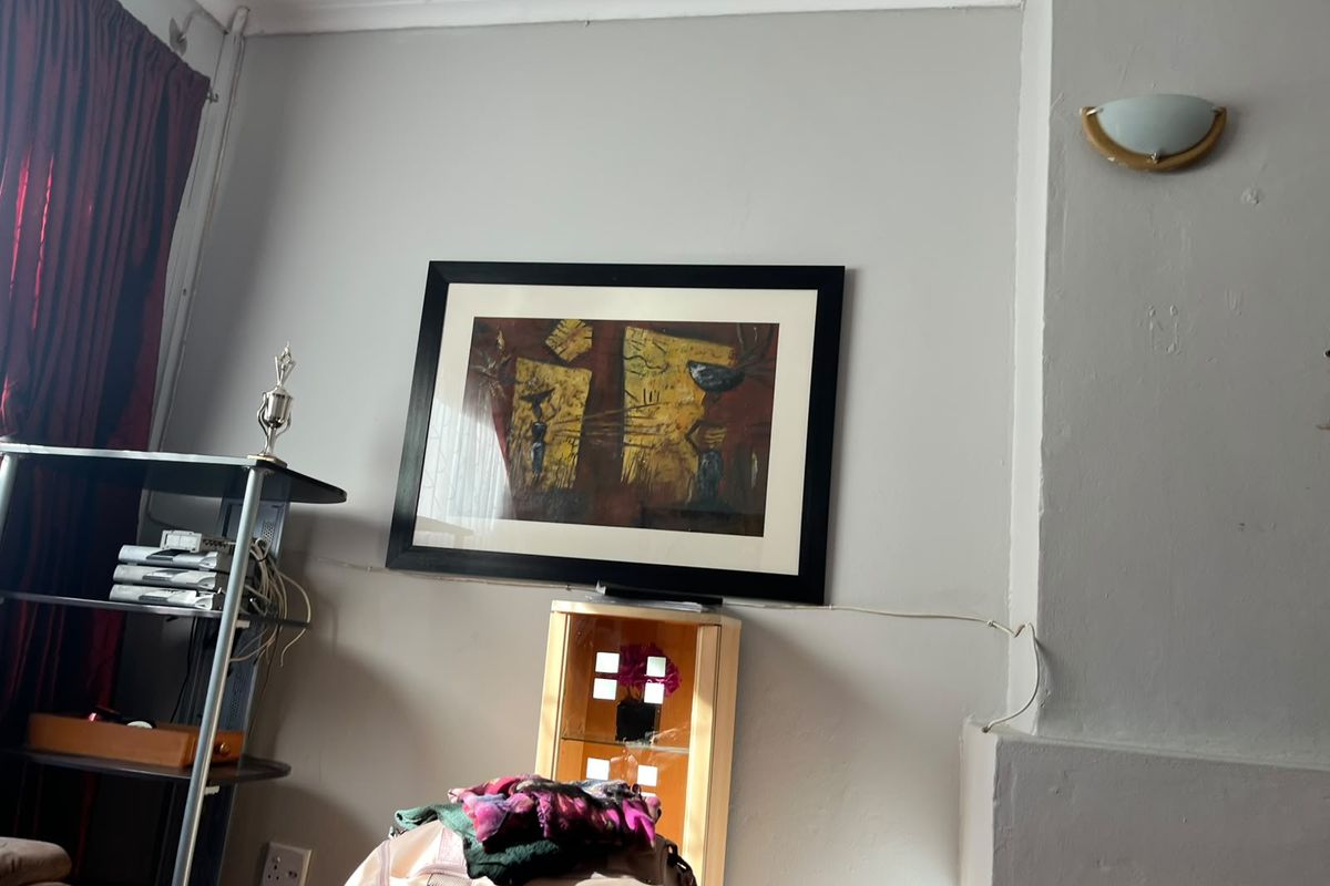 A view of a living room wall featuring a wall-mounted light fixture and electrical outlet.