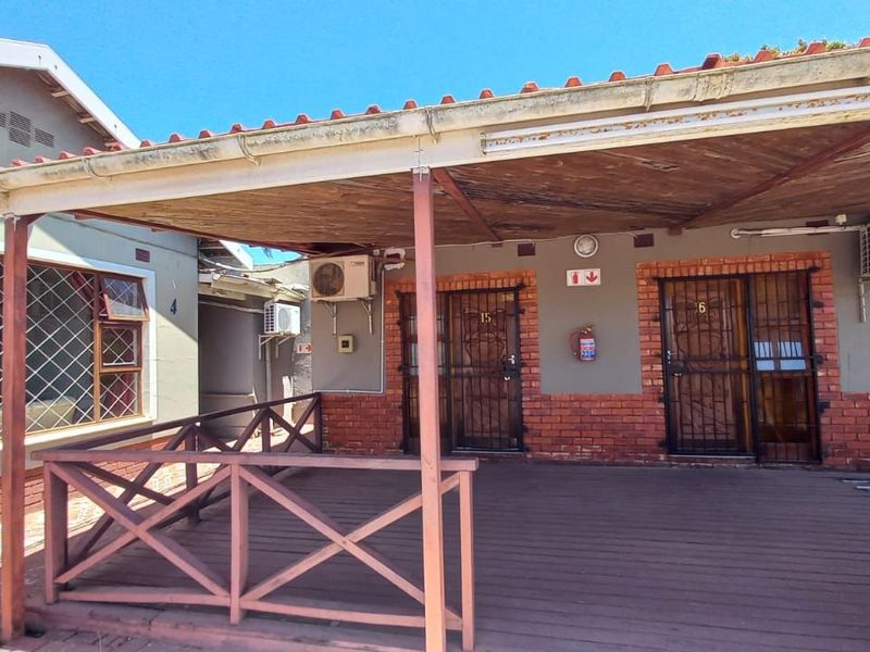 A covered timber patio area providing access to guest units, featuring brick accents, security gates, and wall-mounted air conditioning units.