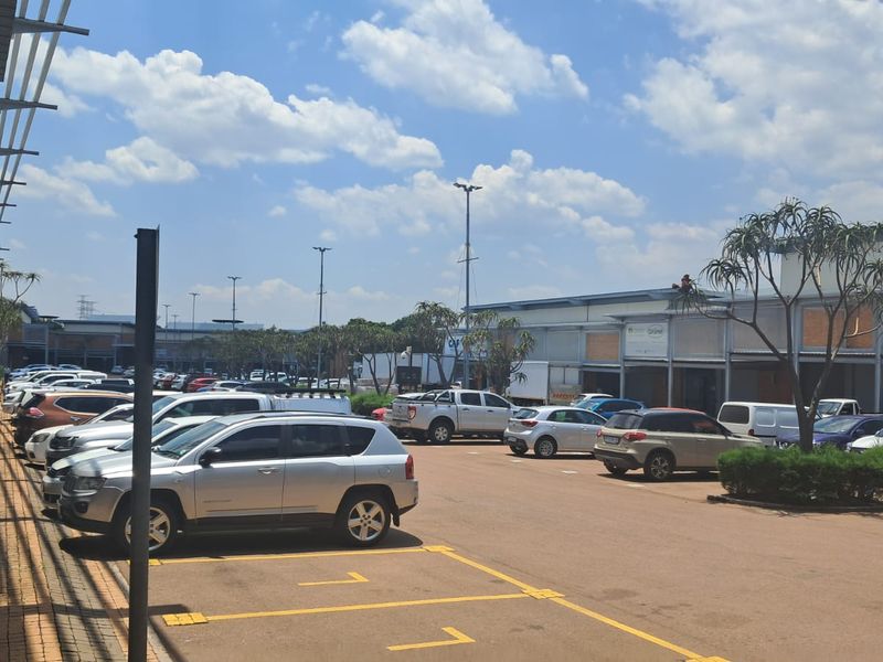 Exterior view of an industrial property featuring a paved parking area, covered walkways, and high mast lighting.
