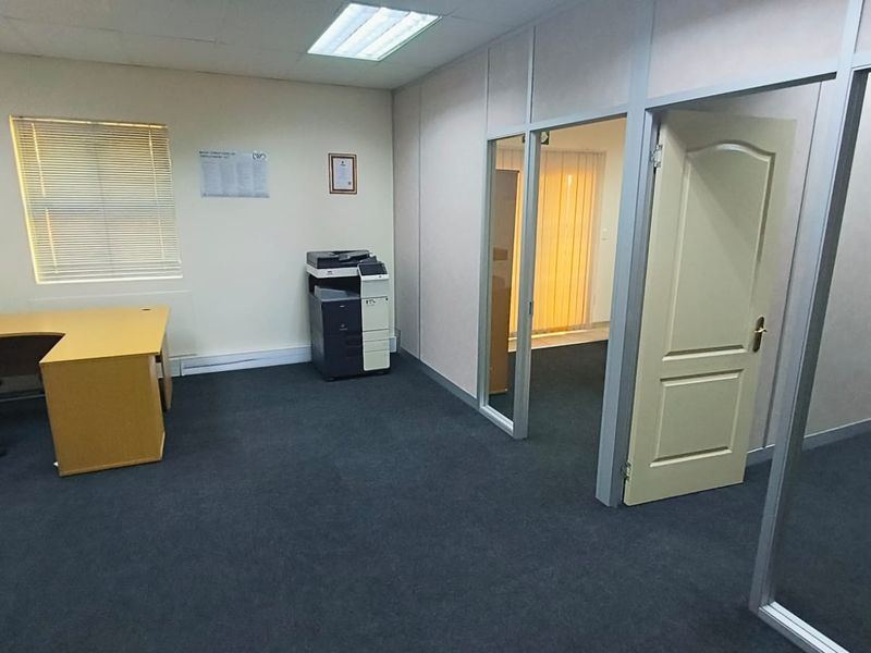A functional office space featuring carpeted flooring, suspended ceilings with recessed lighting, and aluminium-framed glass partitions for a professional layout.