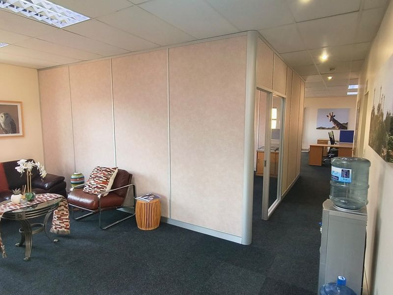 A professional office space featuring modular partition walls, suspended ceiling with recessed lighting, and dark carpet flooring, providing a functional work environment.