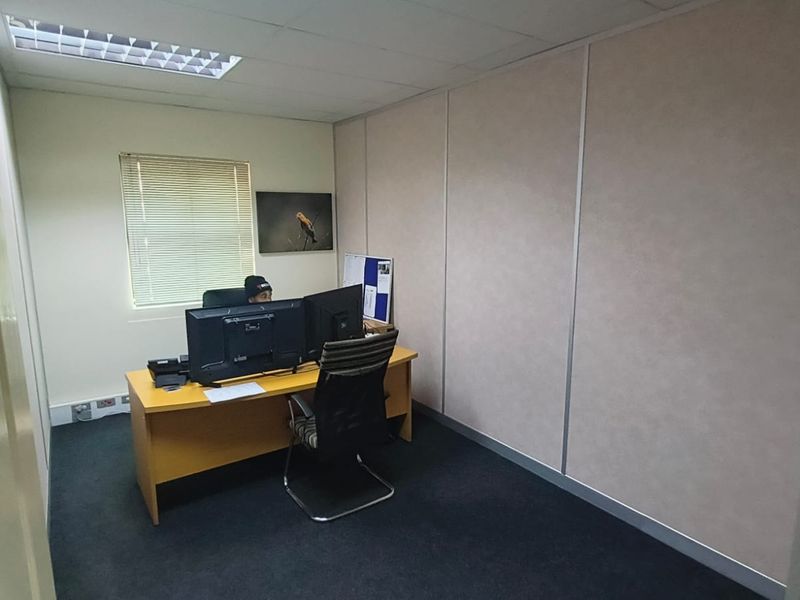 A functional office space featuring modular partition walls, suspended ceiling with recessed lighting, and carpeted flooring.