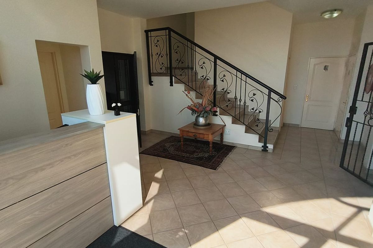 Welcoming office entrance area featuring tiled flooring, a reception desk, and a decorative wrought iron staircase railing.