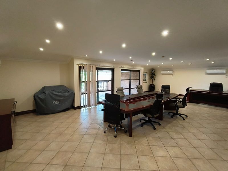 Spacious office area featuring ceramic tiled flooring, recessed lighting, dual split-system air conditioning units, and sliding glass doors providing access to an outdoor patio.