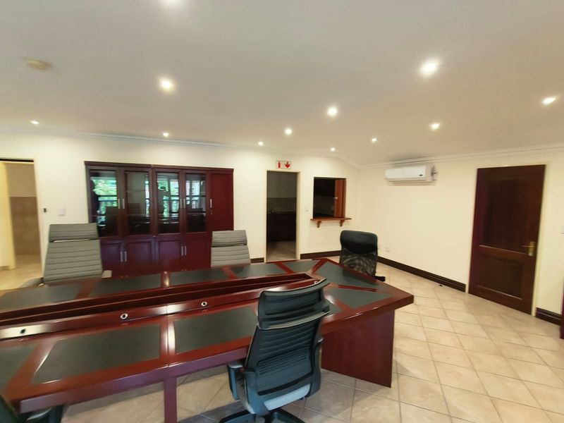 A professional office space featuring tiled flooring, recessed downlighting, built-in cabinetry, and a wall-mounted air conditioning unit.