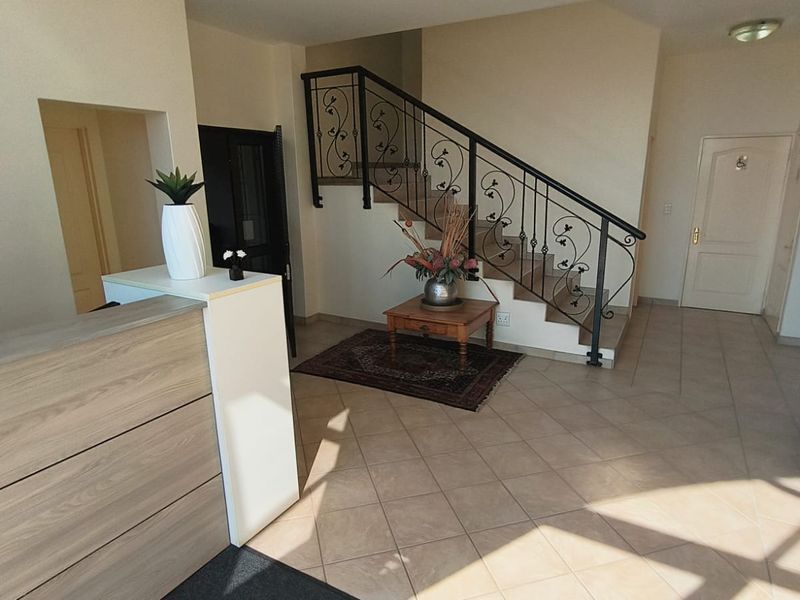 Welcoming office entrance area featuring tiled flooring, a built-in reception desk, and an elegant wrought iron staircase leading to the upper level.
