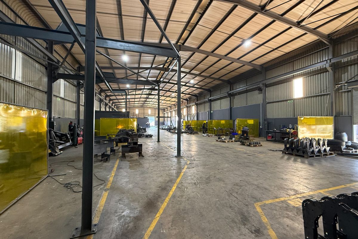 Spacious industrial warehouse featuring a steel portal frame, concrete flooring, and integrated welding screens, suitable for manufacturing or heavy-duty storage operations.