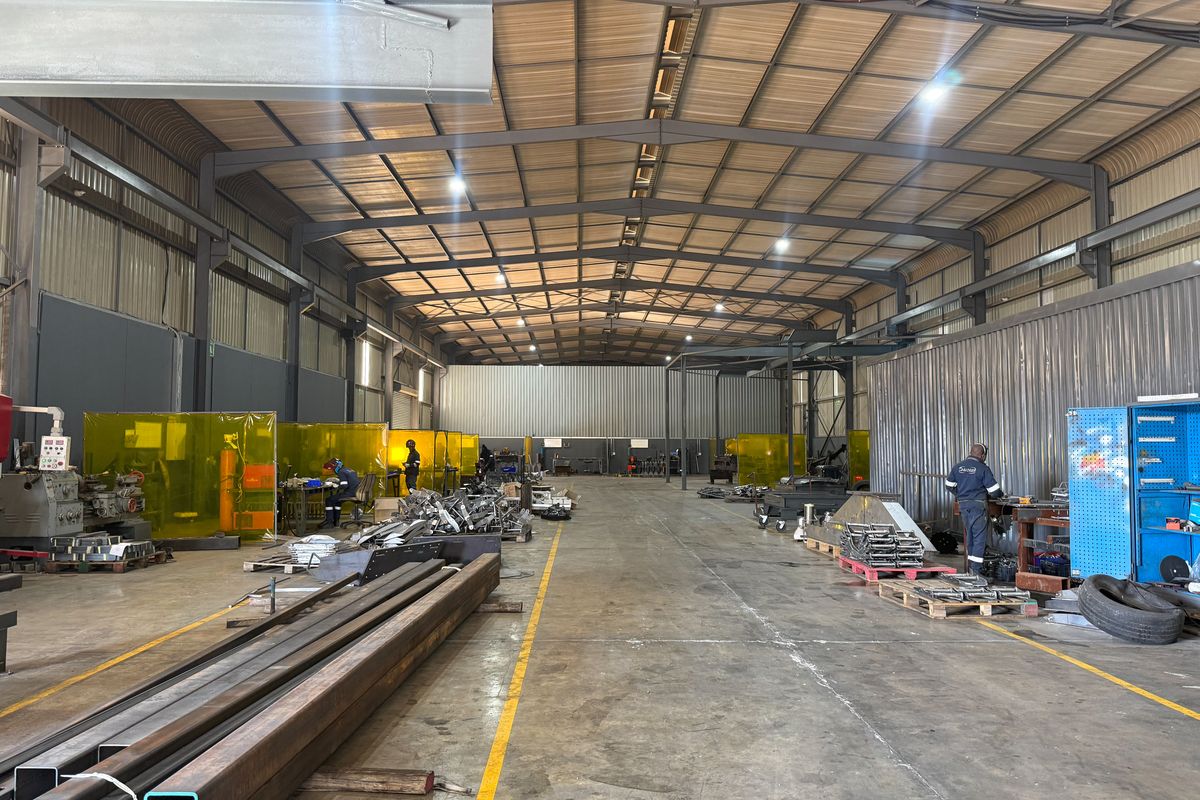 Spacious industrial warehouse facility featuring a high-clearance steel portal frame, concrete flooring, and functional metal wall cladding suitable for manufacturing or storage operations.