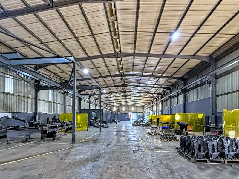 Spacious industrial warehouse featuring a high-clearance steel portal frame, corrugated metal roofing, concrete flooring, and integrated welding screens for operational use.