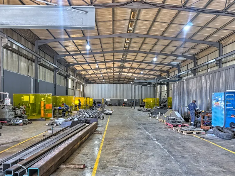 Spacious industrial warehouse facility featuring a high-clearance steel portal frame, concrete flooring, and integrated welding bays for manufacturing operations.
