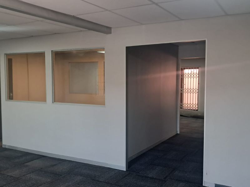 An empty office space featuring neutral walls, carpet tiles, suspended ceilings, and internal glass partitions providing a professional layout.