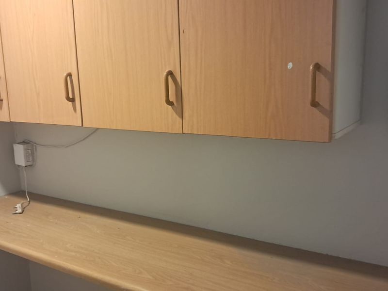A functional office space featuring built-in wooden cabinetry and a laminate work surface, providing practical storage and desk space.