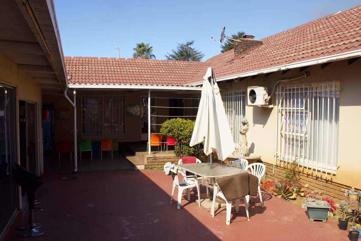 A rear courtyard area featuring a paved patio, tiled roof structure, and security bars on windows, providing an outdoor space for the business premises.