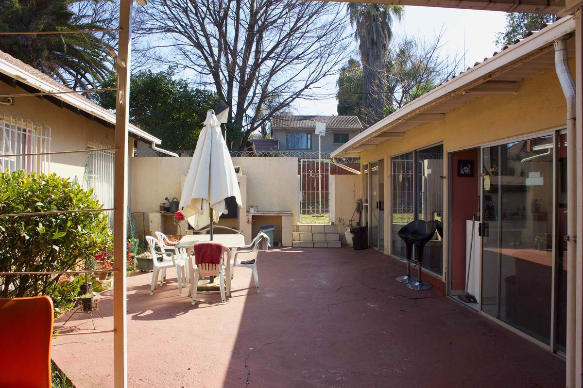 Outdoor patio area featuring a built-in braai, concrete flooring, and sliding door access to the main building structure.