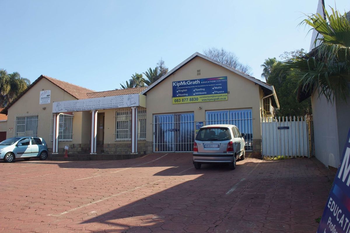 Front exterior view of a commercial property featuring a paved driveway, security gates, and signage for an education centre.