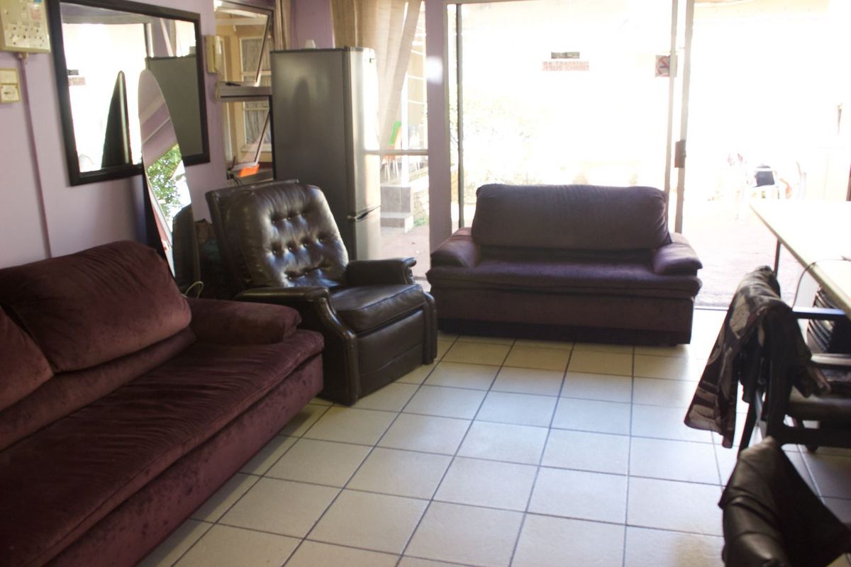 A living area featuring tiled flooring and a large sliding glass door providing access to the exterior.