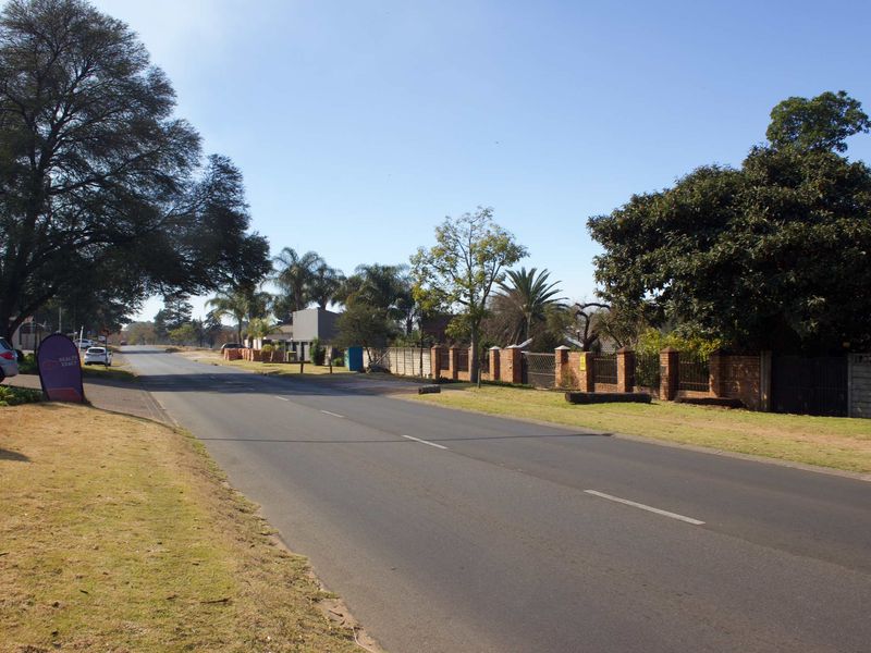 A street view showing the road, verge, and brick boundary wall of the property.