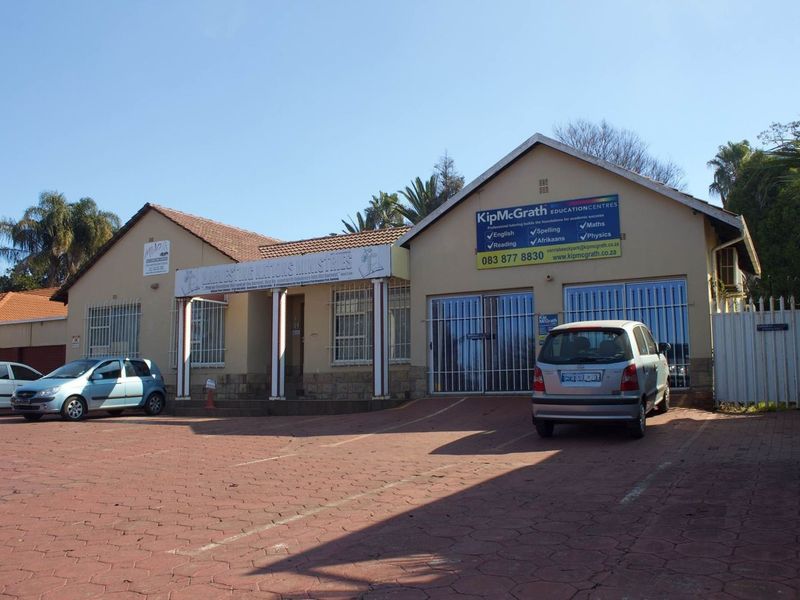 Front elevation of a commercial property featuring a paved parking area, covered entrance, and security-fitted windows and doors.
