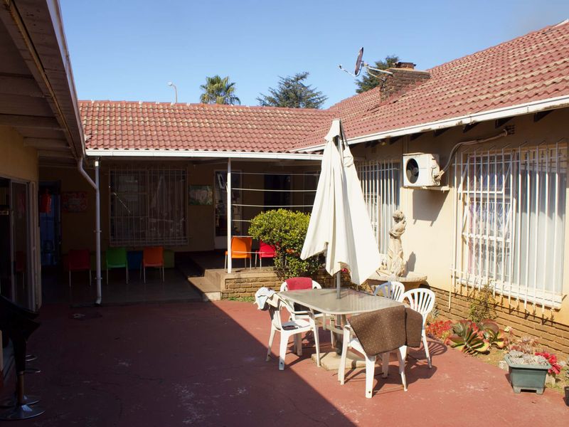 A rear courtyard area featuring a paved patio, tiled roof structure, and security bars on windows, providing an outdoor space for the business premises.