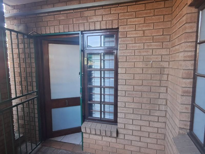 Exterior view of the office entrance featuring a brick facade, timber-framed door with frosted glass, and security gate.