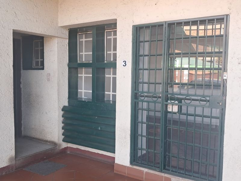 Entrance area of an office unit featuring a security gate, tiled flooring, and exterior wall lighting.
