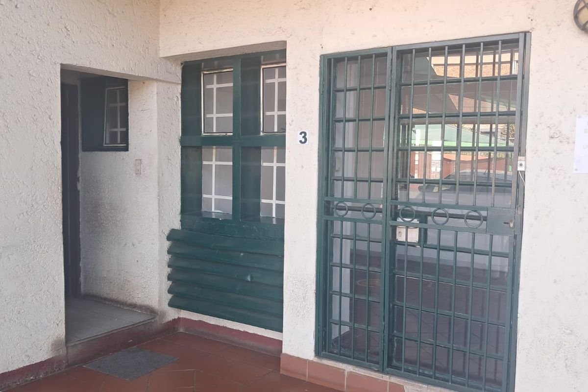 Entrance area of an office unit featuring a security gate, tiled flooring, and exterior wall lighting.