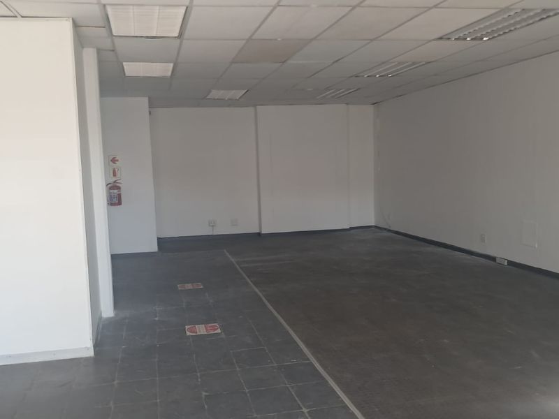 An empty, open-plan office space featuring a suspended ceiling, recessed lighting, and tiled flooring, ready for custom fit-out.