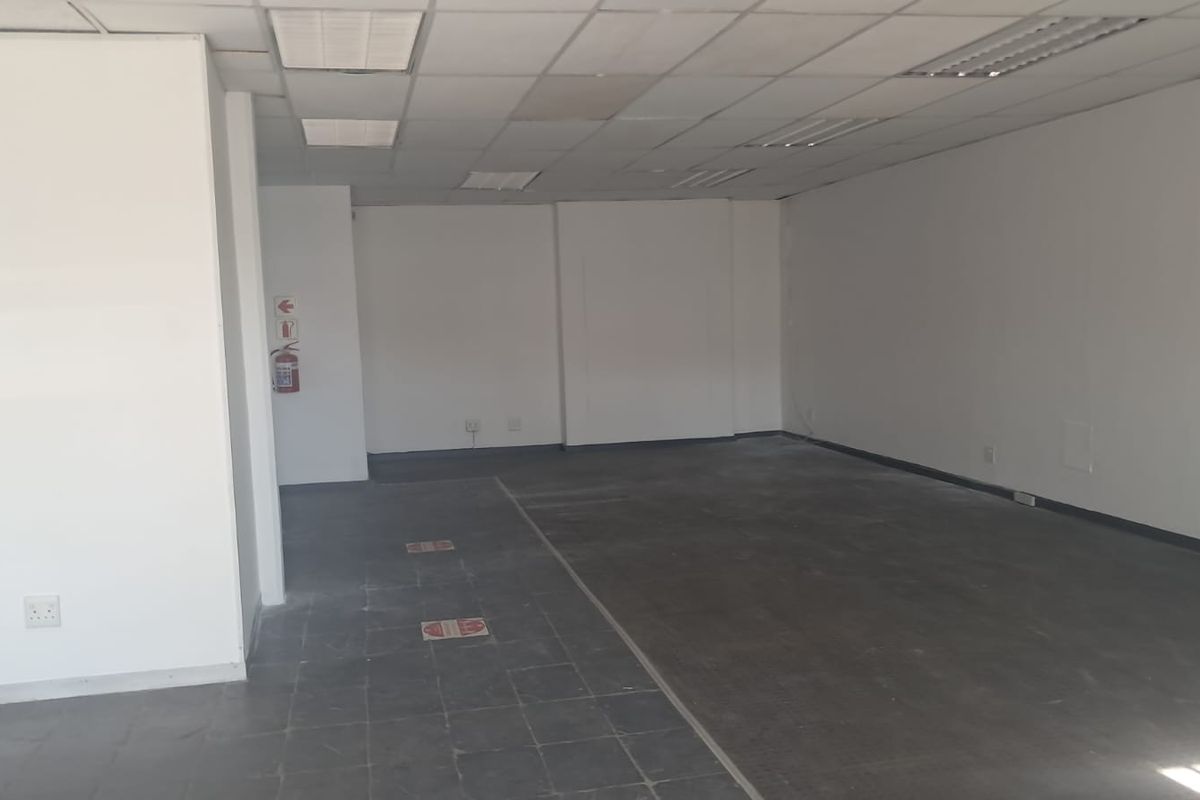 An empty, open-plan office space featuring a suspended ceiling, recessed lighting, and tiled flooring, ready for custom fit-out.