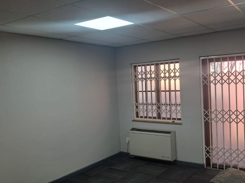 A vacant office space featuring a suspended ceiling, recessed lighting, carpeted flooring, and secure window and door access.