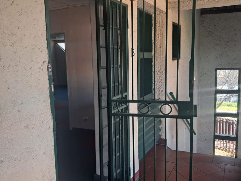 Entrance area featuring a metal security gate, tiled flooring, and textured wall finishes leading into the office space.