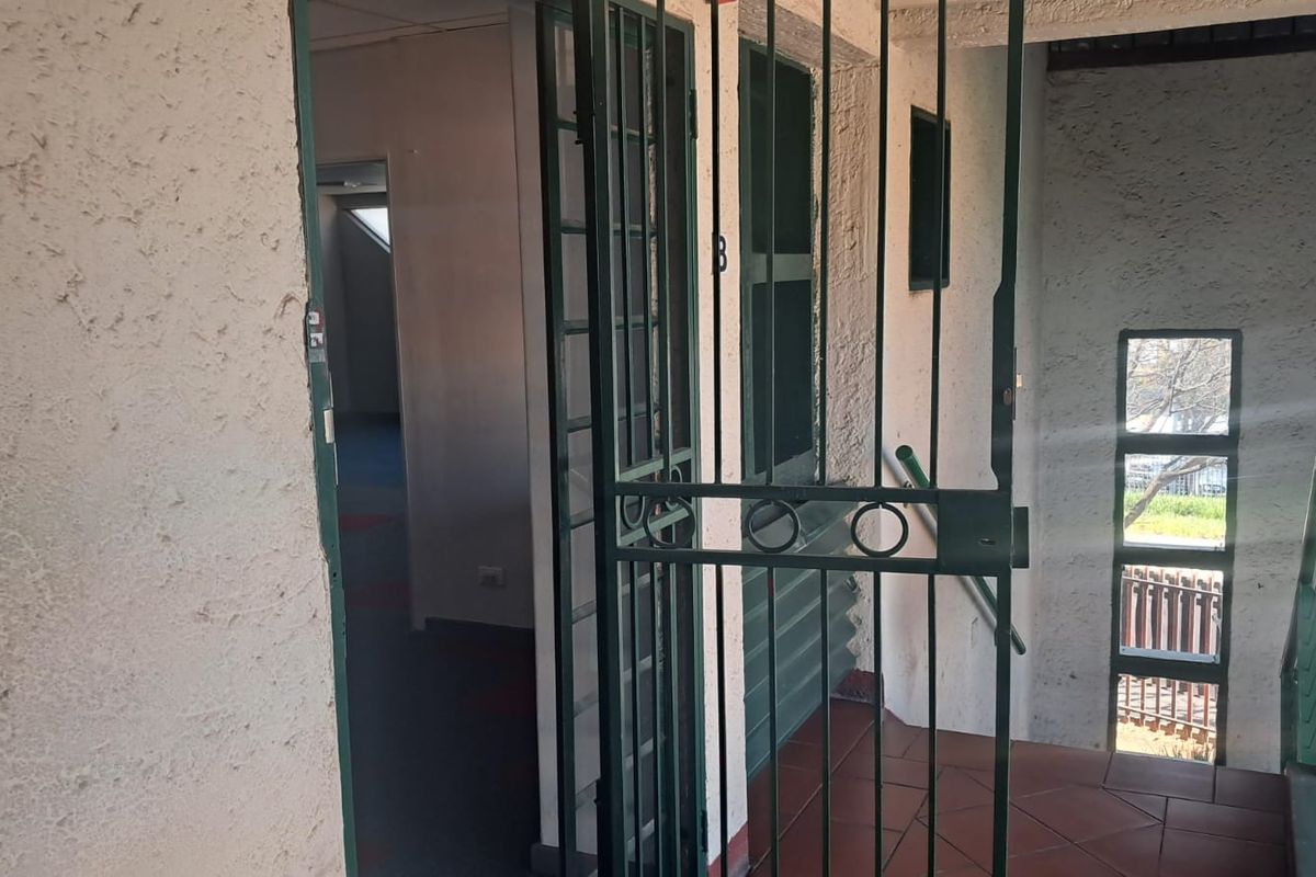 Entrance area featuring a metal security gate, tiled flooring, and textured wall finishes leading into the office space.