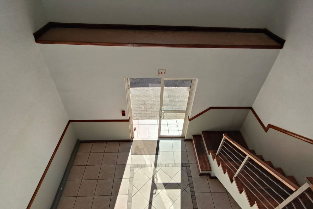 An entrance foyer featuring a staircase with a metal balustrade, tiled flooring, and a glass exit door leading to the exterior.