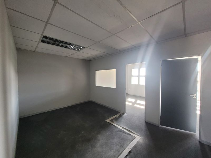 An empty office space featuring a suspended ceiling, recessed lighting, and an internal window, ready for custom fit-out.