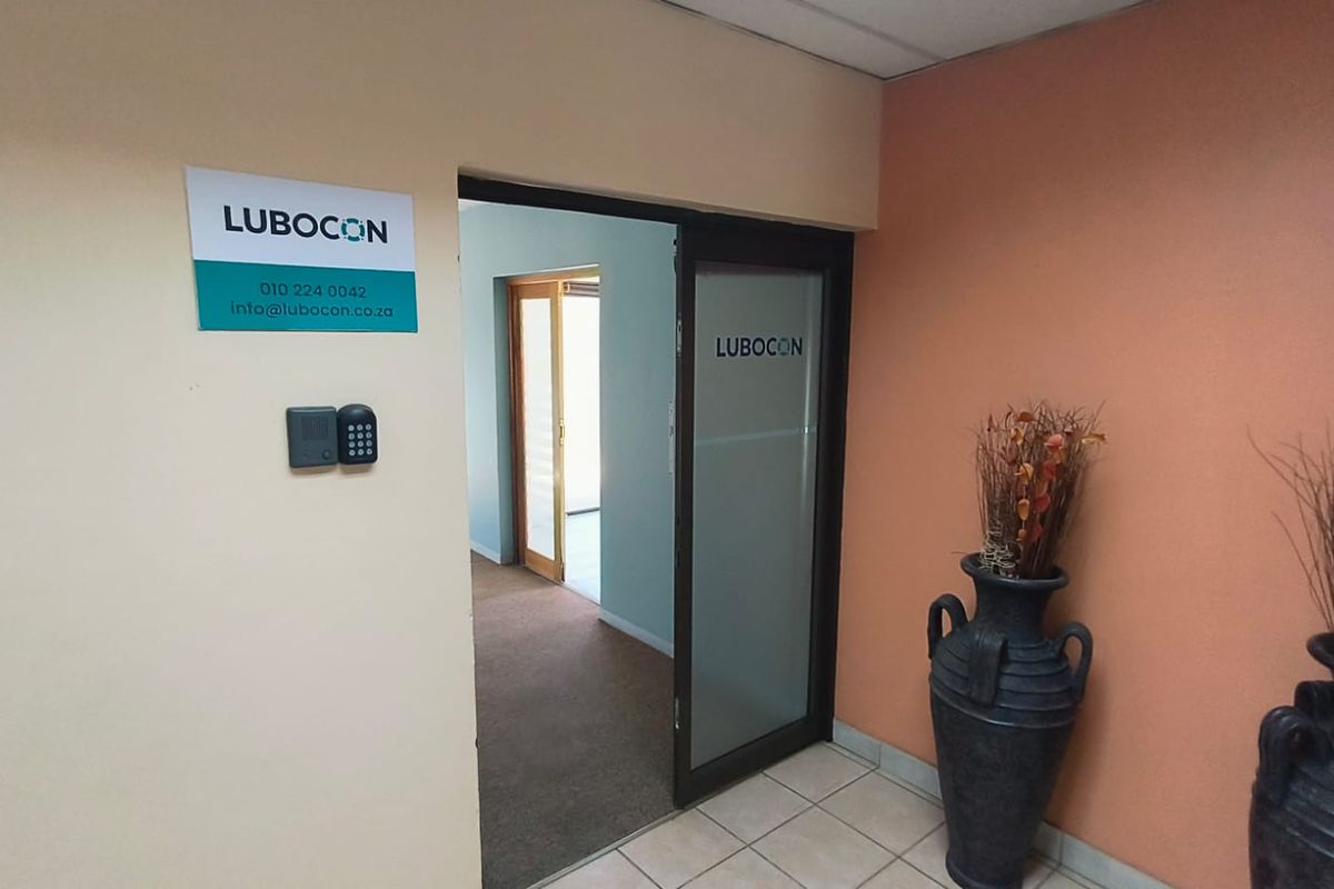 Office entrance area featuring a glass door, access control system, and a combination of tiled and carpeted flooring.