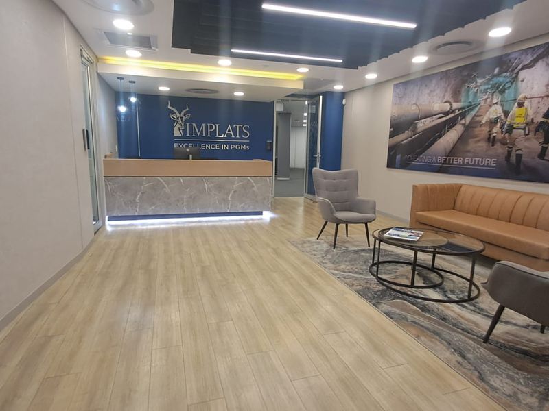 Modern office reception area featuring a professional reception desk, recessed lighting, and high-quality laminate flooring in a clean, corporate environment.