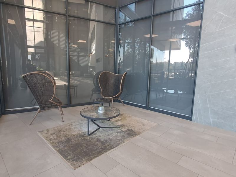 Modern office reception or breakout area featuring floor-to-ceiling glass walls, large-format porcelain floor tiles, and a contemporary stone feature wall.