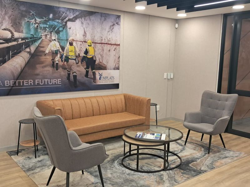 A modern, well-maintained office waiting area featuring contemporary seating, recessed lighting, and professional wall branding.