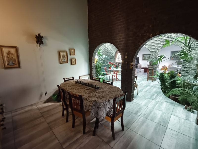 Dining area featuring exposed brick arches and tiled flooring, opening into an internal courtyard space.