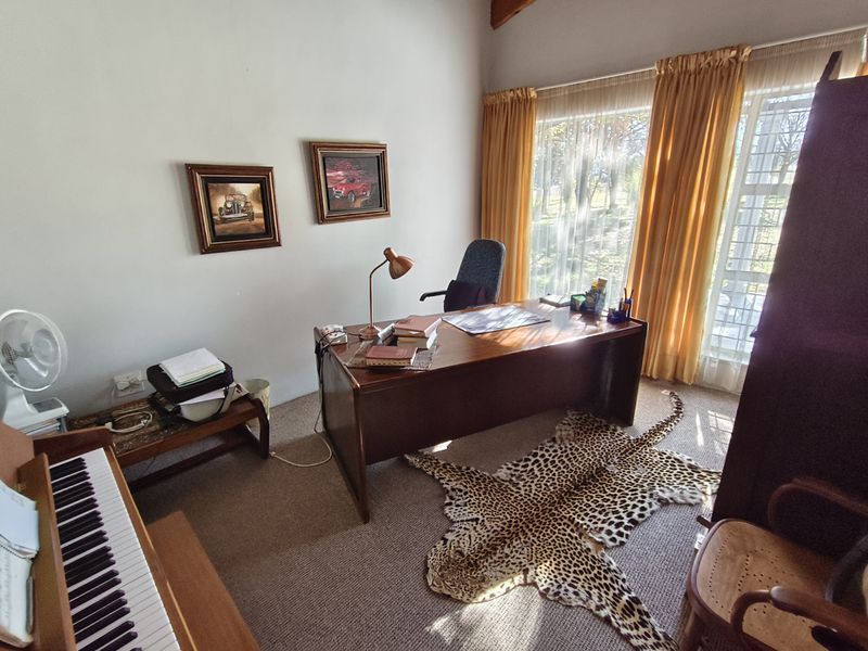 A home office featuring a vaulted ceiling, carpeted flooring, and large windows that provide ample natural light.