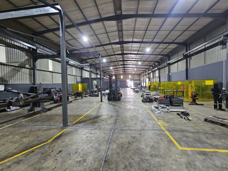 Spacious industrial warehouse featuring a steel portal frame structure, concrete flooring, and integrated welding bays, suitable for manufacturing or heavy-duty storage operations.