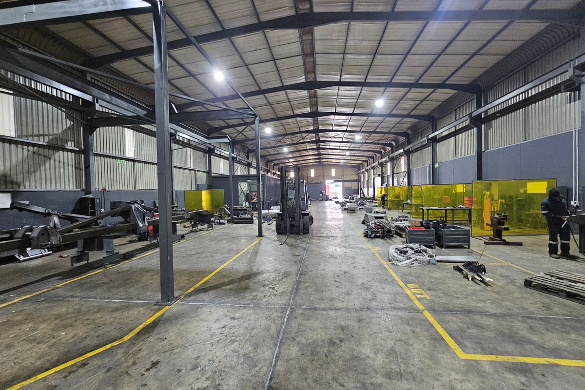 Spacious industrial warehouse featuring a steel portal frame structure, concrete flooring, and integrated welding bays, suitable for manufacturing or heavy-duty storage operations.