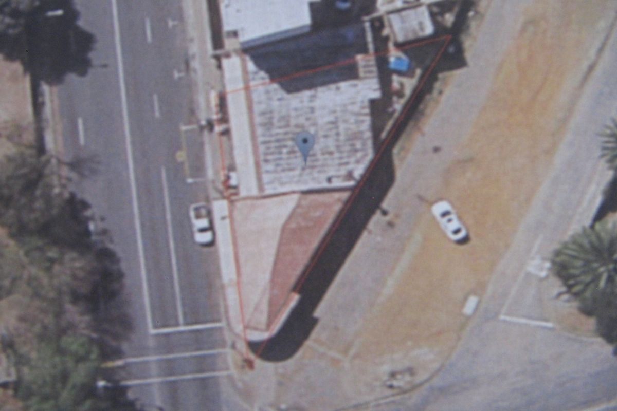Aerial view of the commercial property showing the building footprint, roof condition, and adjacent paved parking area.