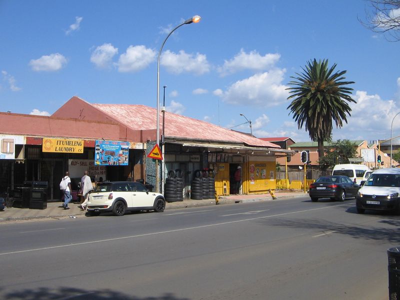 Street-level view of a retail property featuring a metal roof and shopfronts along a busy road.
