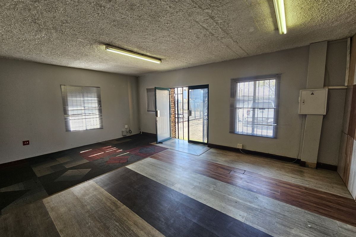 An empty open-plan retail space featuring textured ceilings, fluorescent lighting, and a secure entrance, offering a blank canvas for commercial customization.